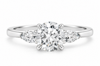 Three-stone round brilliant diamond engagement ring in polished silver with a large center diamond and two pear-shaped side diamonds in a classic setting.