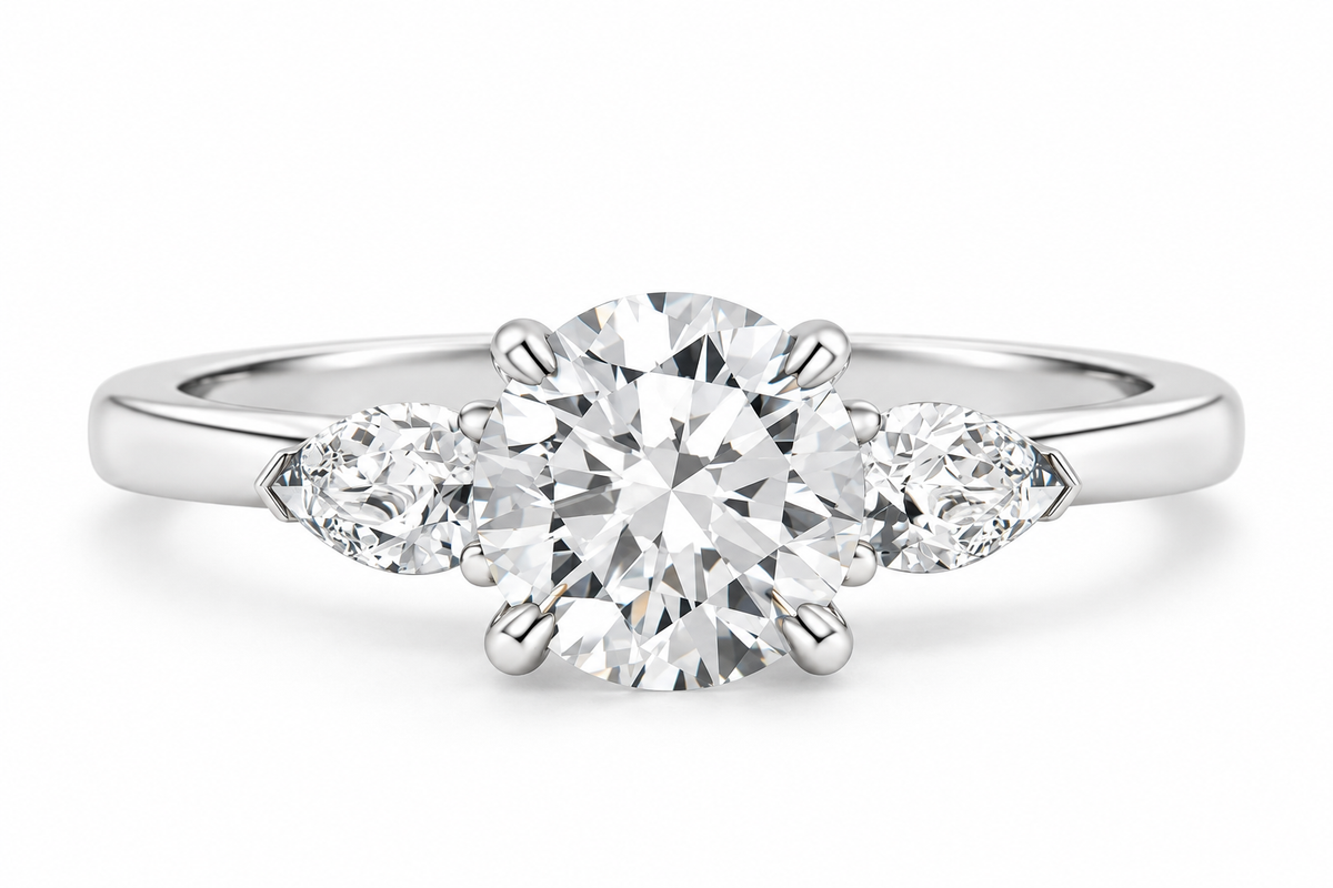 Three-stone round brilliant diamond engagement ring in polished silver with a large center diamond and two pear-shaped side diamonds in a classic setting.