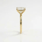 Side profile view of a radiant cut solitaire diamond engagement ring set in a polished yellow gold four-prong basket setting with a slender plain band.