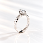 Three-quarter view of a teardrop engagement ring with a pear cut diamond center stone in a five-prong white gold setting and round side stones on a thick band