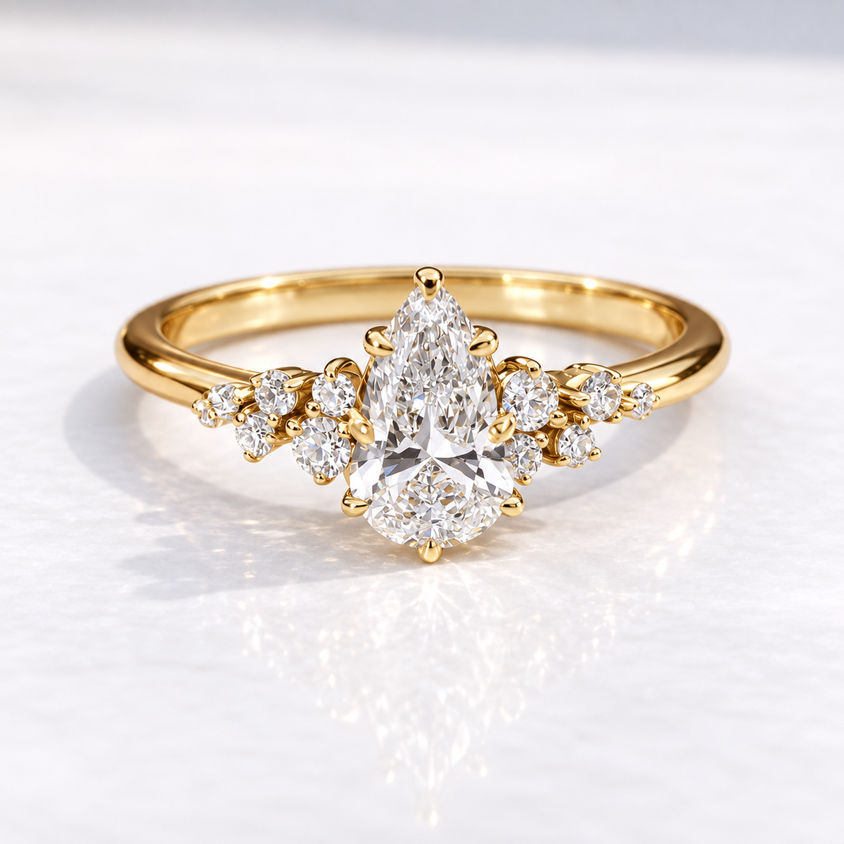 Gold pear-cut diamond engagement ring with a floral cluster of round accent stones on a polished gold band