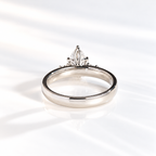 Back view of a teardrop solitaire engagement ring showing the prong setting of a pear cut diamond and the thick polished white gold band