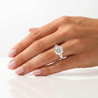 Round brilliant cut diamond engagement ring set in yellow gold, flanked by tapered baguette side stones and worn on a hand.