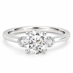 Three-stone round brilliant cut diamond engagement ring in polished silver, featuring a large center diamond with two smaller side diamonds in a classic three-stone setting on a sleek band