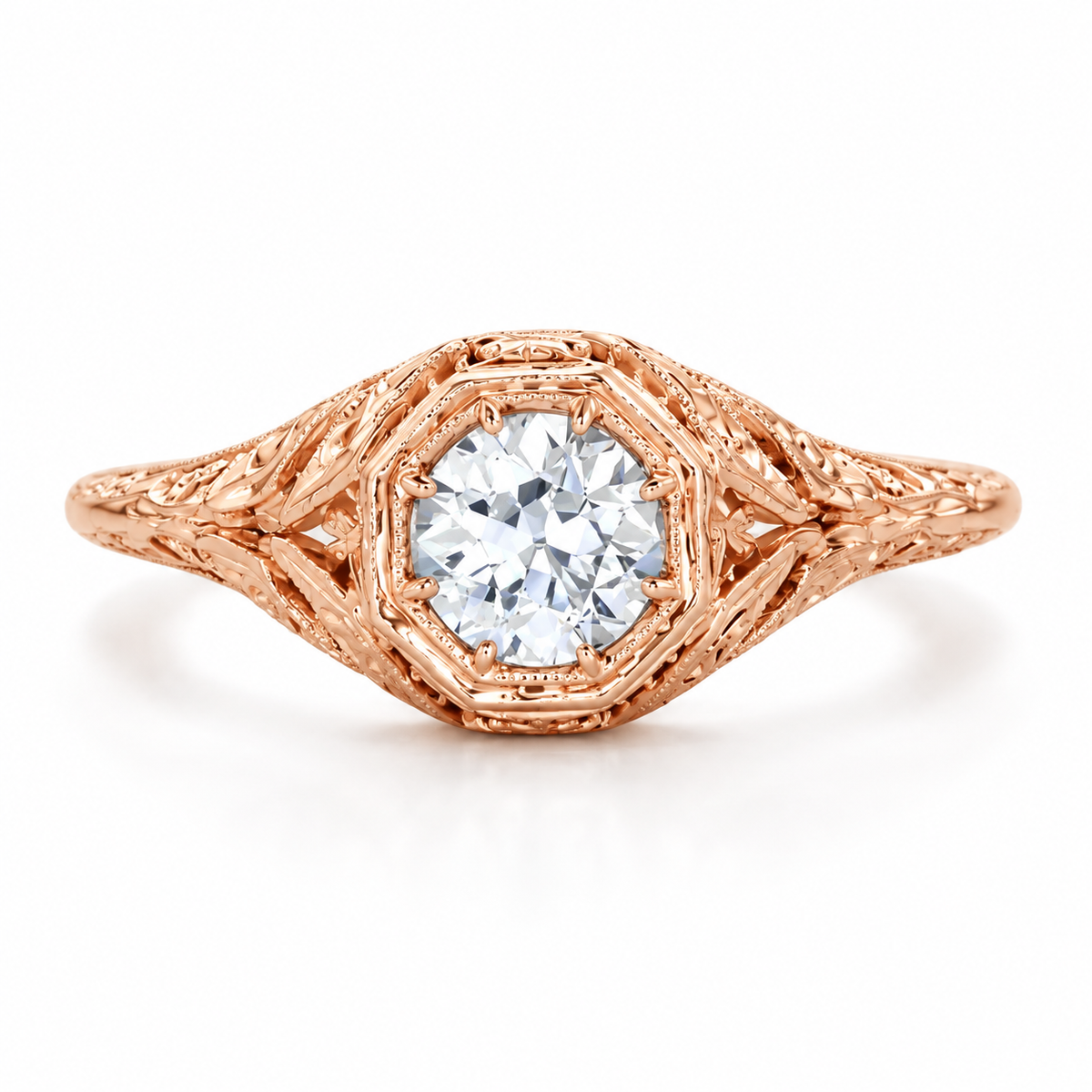 Vintage inspired rose gold engagement ring featuring a round brilliant diamond, intricate filigree detailing, engraved openwork band design, milgrain accents, and a luxurious warm rose gold finish with antique style