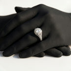 Vintage Art Deco peekaboo engagement ring featuring an Old European cut diamond set in an intricate filigree openwork white gold or platinum band, displayed on black-gloved hands.
