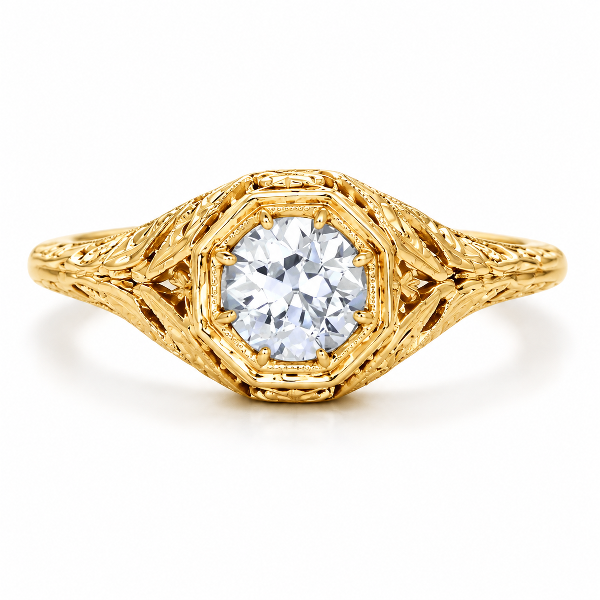 Vintage inspired yellow gold engagement ring featuring a round brilliant diamond, ornate filigree design, engraved leaf-like details, milgrain accents, and a luxurious antique style setting.