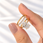 Fingers with a nude manicure holding a yellow gold oval diamond solitaire ring and a stacked wedding band of round diamonds