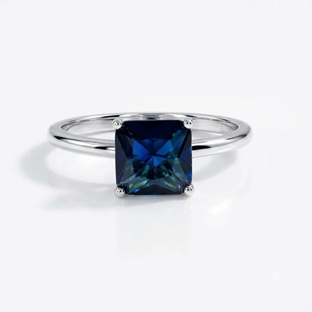 A square-cut dark blue gemstone ring set in a polished silver band, photographed on a clean white background.